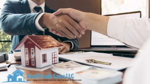 two people shaking hands over a house model | Real Estate LLC