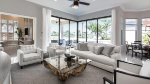 a living room with white furniture and a ceiling fan